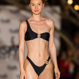Full-length front view of an athletic model wearing the SBOVIA Nero Classico black single-shoulder bikini set with custom luxury metallic hardware